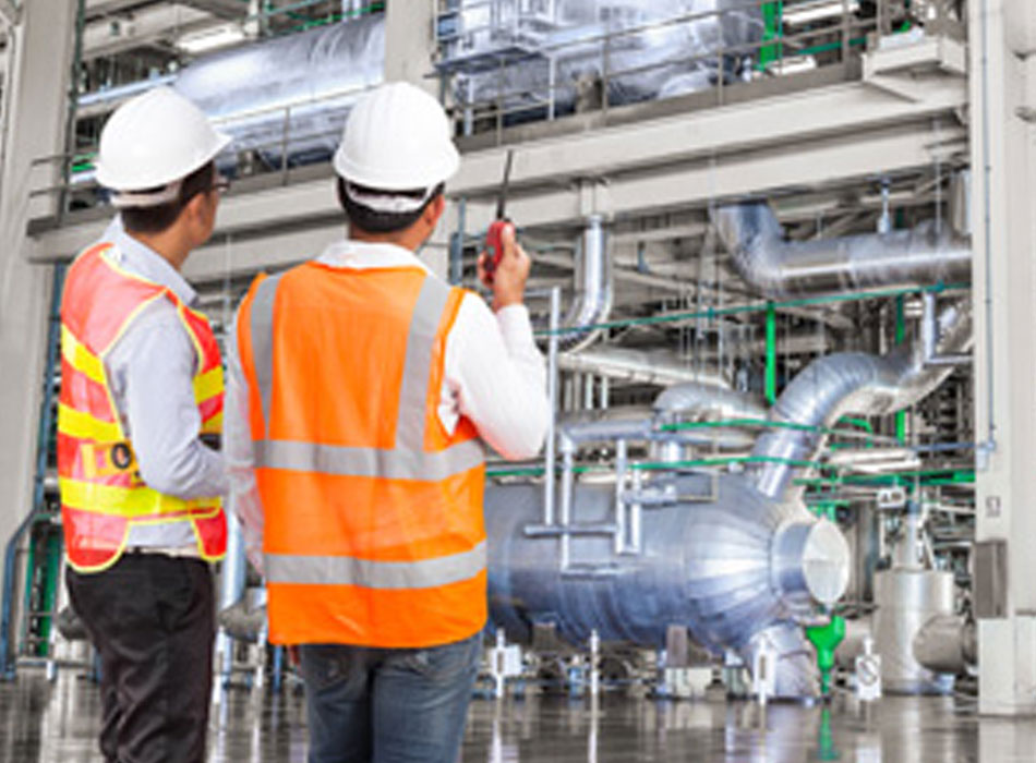 Two people standing in front of industrial electrical equipment