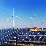 Wind turbines and solar panels in a field with blue sky in the background