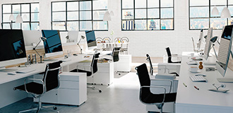 interior view of an open office work environment with desks, chairs, and computer monitors