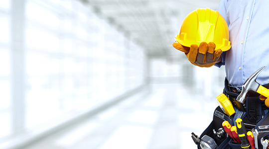 construction worker holding bright yellow hard hat and hammer with full tool belt
