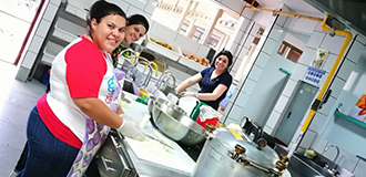 Drei weibliche Panduit-Mitarbeiterinnen lächeln und kochen für die Bewohner