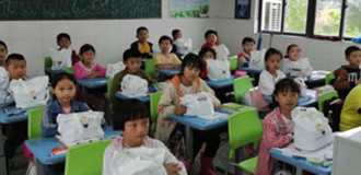 Klassenzimmer der Wangjian-Grundschule in China mit Kindern, die mit Panduit-Gesundheitspaketen am Schreibtisch sitzen