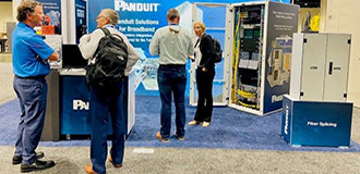 people gather in the panduit booth at a broadband trade show