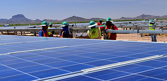 Solar panel array in a field with construction workers outside  