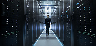 Person walking between two rows of black data center cabinets in a data center